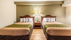 Une chambre d’hôtel avec deux lits, une table de chevet et une lampe fixée au mur.