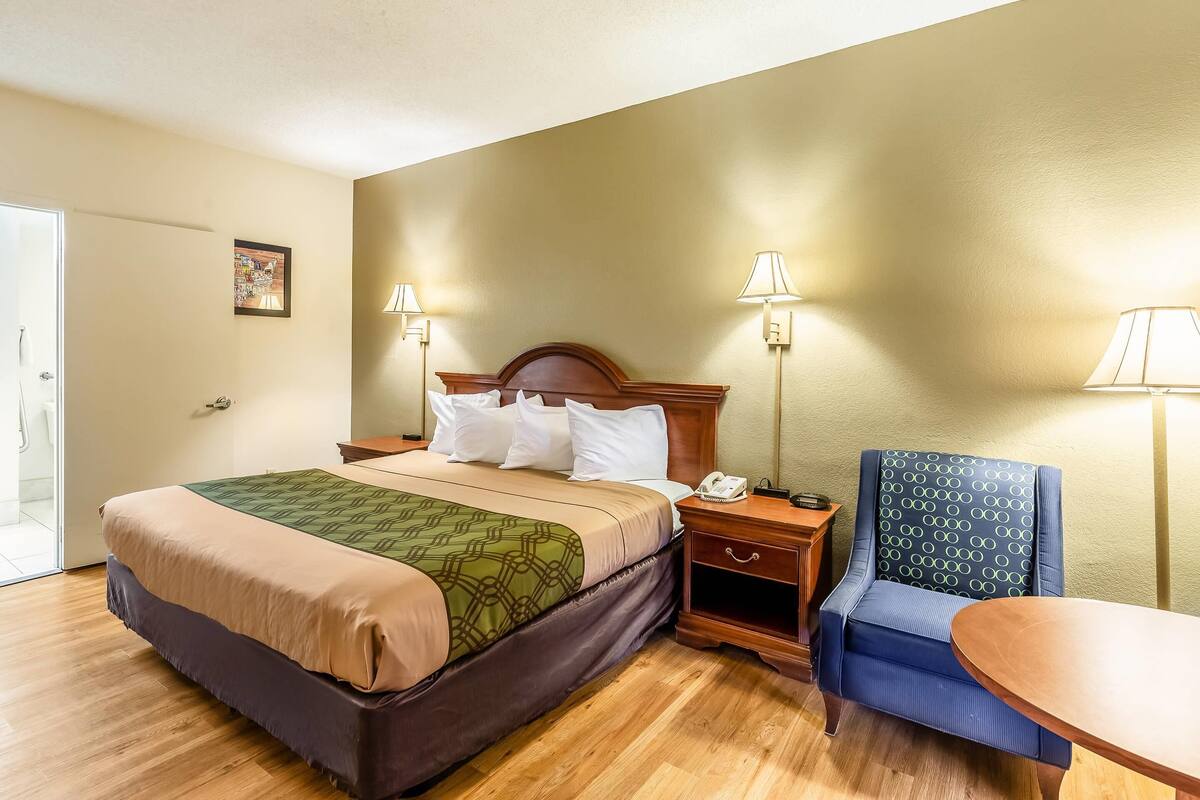 A hotel room with a bed, two bedside tables, a chair, and a small table.