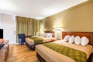Habitación de hotel con dos camas, un escritorio, una silla y un televisor.
