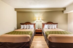 A hotel room with two single beds, a nightstand with a lamp, and a wooden headboard. - Econo Lodge Lake City-North (Lake City)