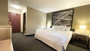 A hotel room with a large bed, two bedside tables with lamps, a desk with a chair, a door, and a wall with a road map mural. - Super 8 by Wyndham St Charles (St. Charles)