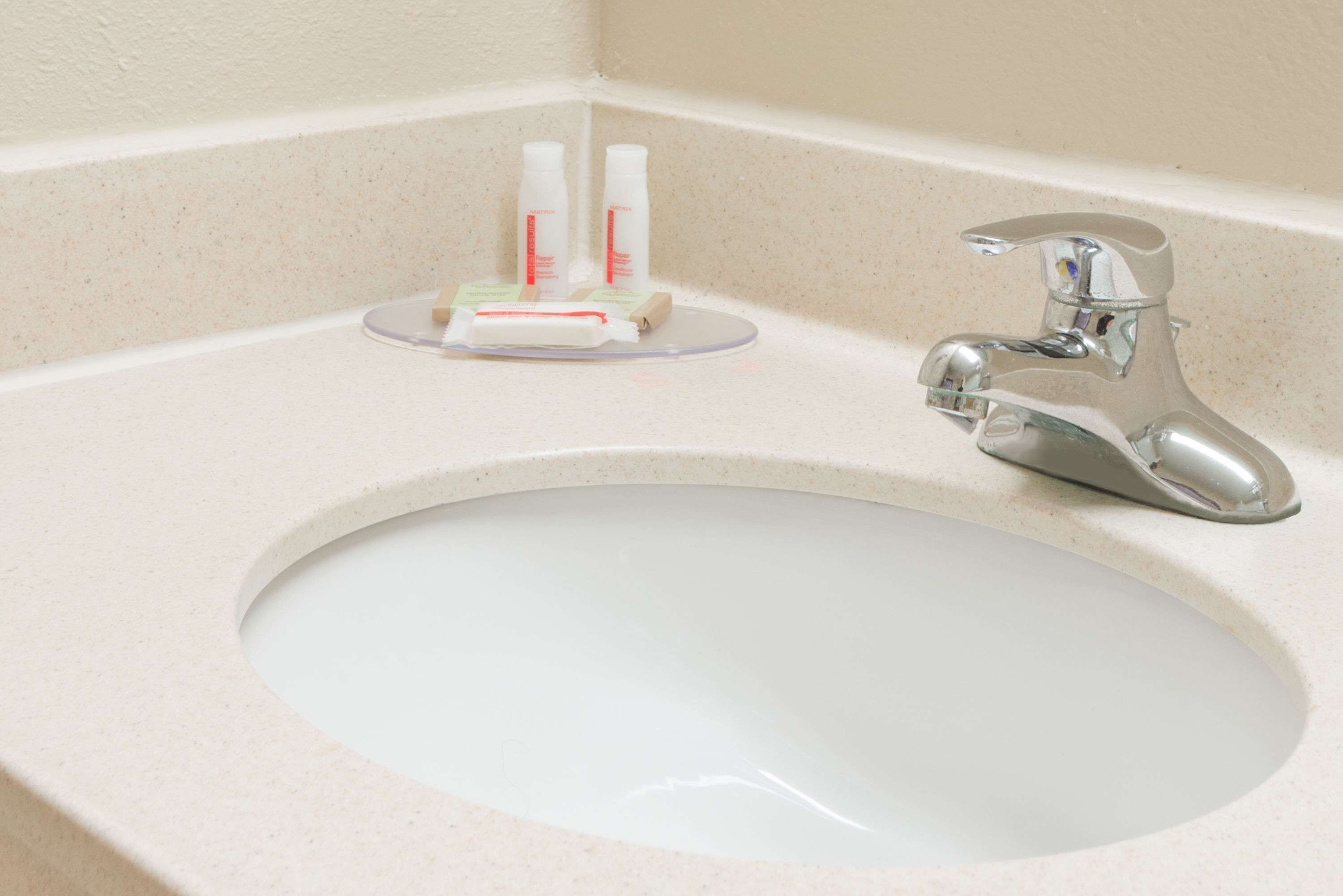 A bathroom sink with a chrome faucet and a soap dish with two bottles.