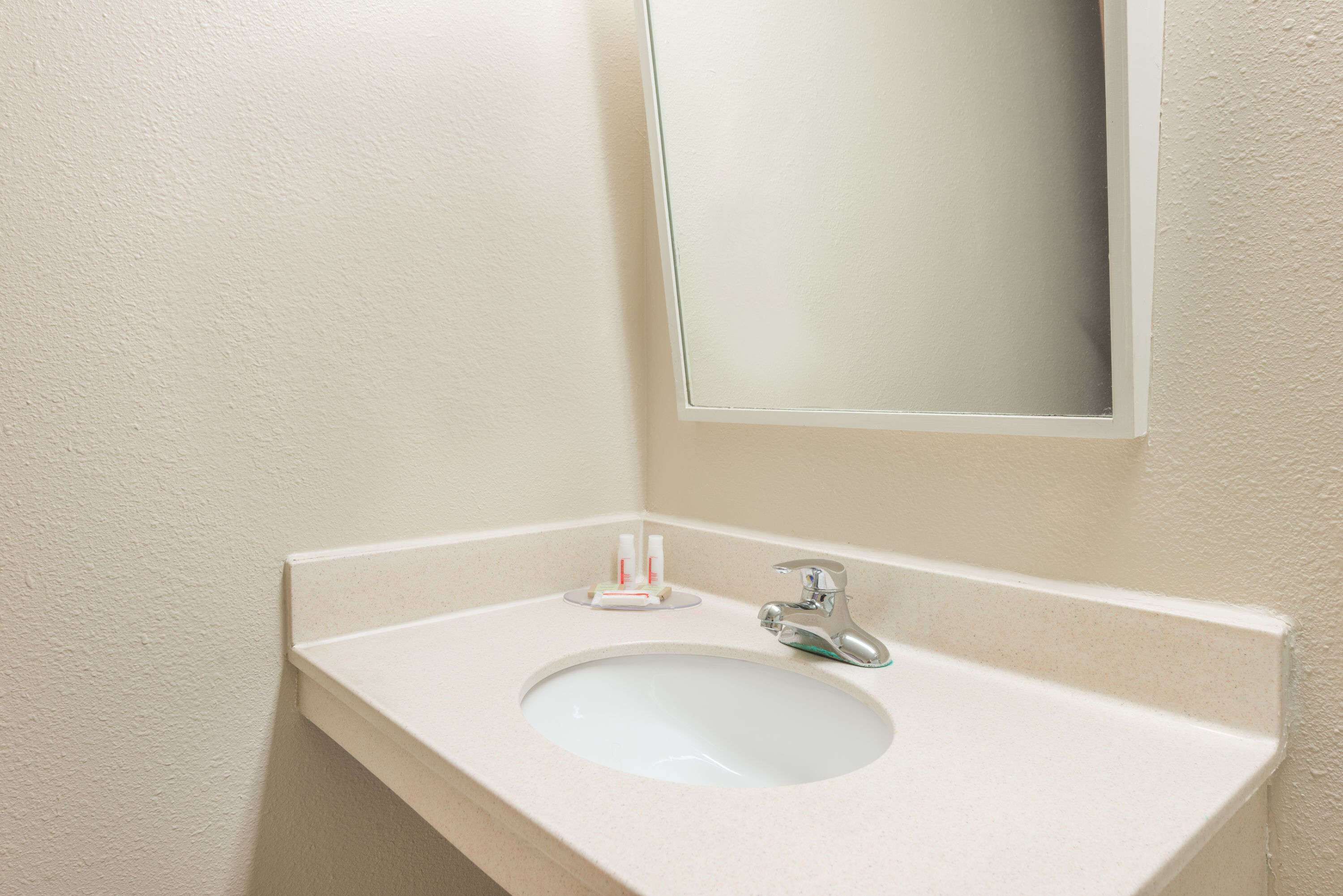 A bathroom sink with a mirror, a faucet, and two toothbrushes on a white countertop.