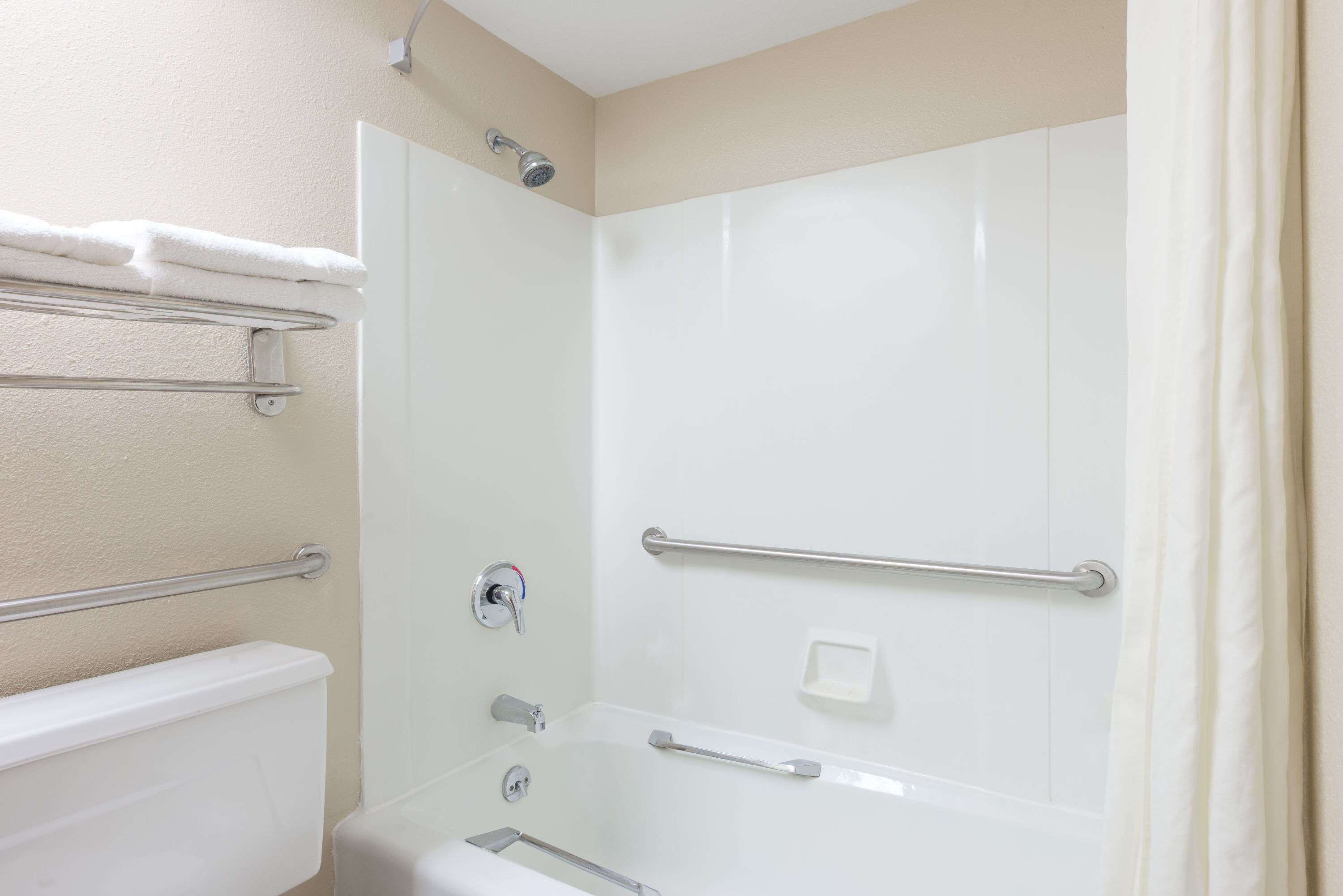 A bathroom with a bathtub, a shower, and a toilet. There are towel racks and a soap dish.