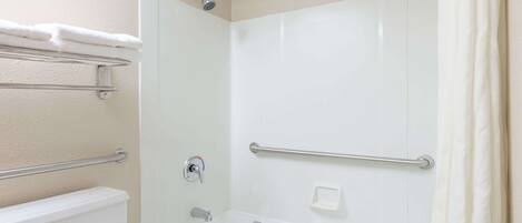 A bathroom with a bathtub, a shower, and a toilet. There are towel racks and a soap dish.