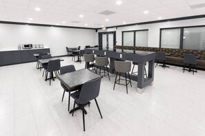 Un espace repas moderne avec des tables et des chaises, un comptoir et un banc pour s’asseoir.