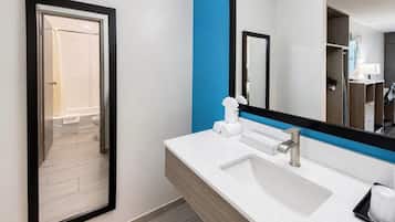 A modern bathroom with a white sink, a large mirror, and a blue accent wall.