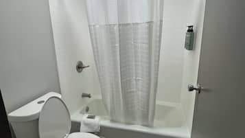A bathroom with a toilet, a bathtub, and a shower curtain.