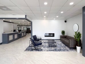 Un hall d’entrée moderne comprenant un comptoir de réception, un espace salon et un téléviseur à écran plat fixé au mur.
