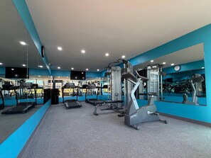 Une salle de sport équipée de tapis de course, de vélos elliptiques et de matériel de musculation.