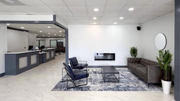 Un lobby moderno con un mostrador de recepción, un área de descanso y un televisor de pantalla plana montado en la pared.
