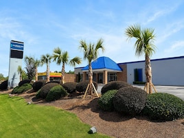 Un hotel con techo azul, palmeras y un letrero del Clarion Inn.
