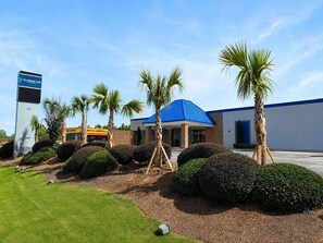 Un hôtel avec un toit bleu, des palmiers et une enseigne indiquant « Clarion Inn ».