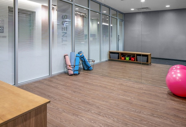 Une pièce moderne avec un plancher en bois, un comptoir d’accueil, du matériel d’exercice et un mur orné d’un motif décoratif.