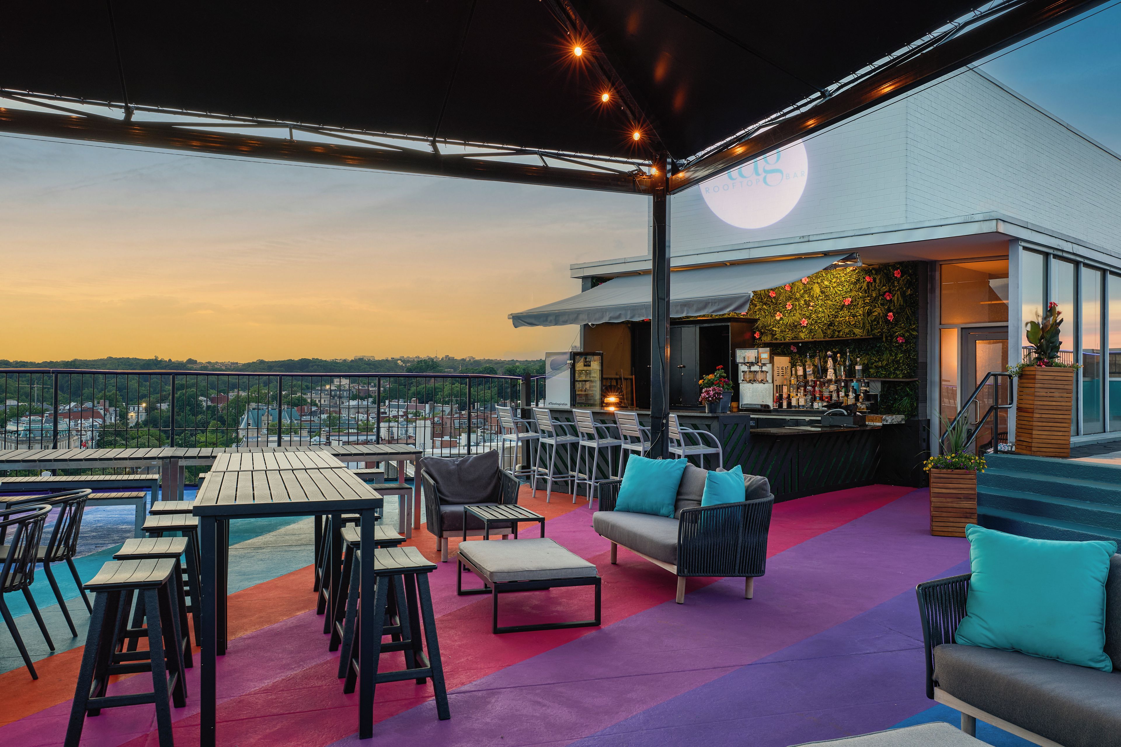 A rooftop bar with outdoor seating, a pool, and a view of the city skyline.