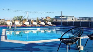 A rooftop pool with lounge chairs and string lights.