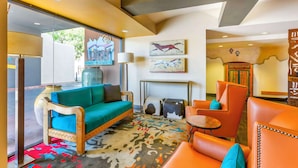 A lobby with a sofa, chairs, a patterned rug, artwork, and a fireplace.