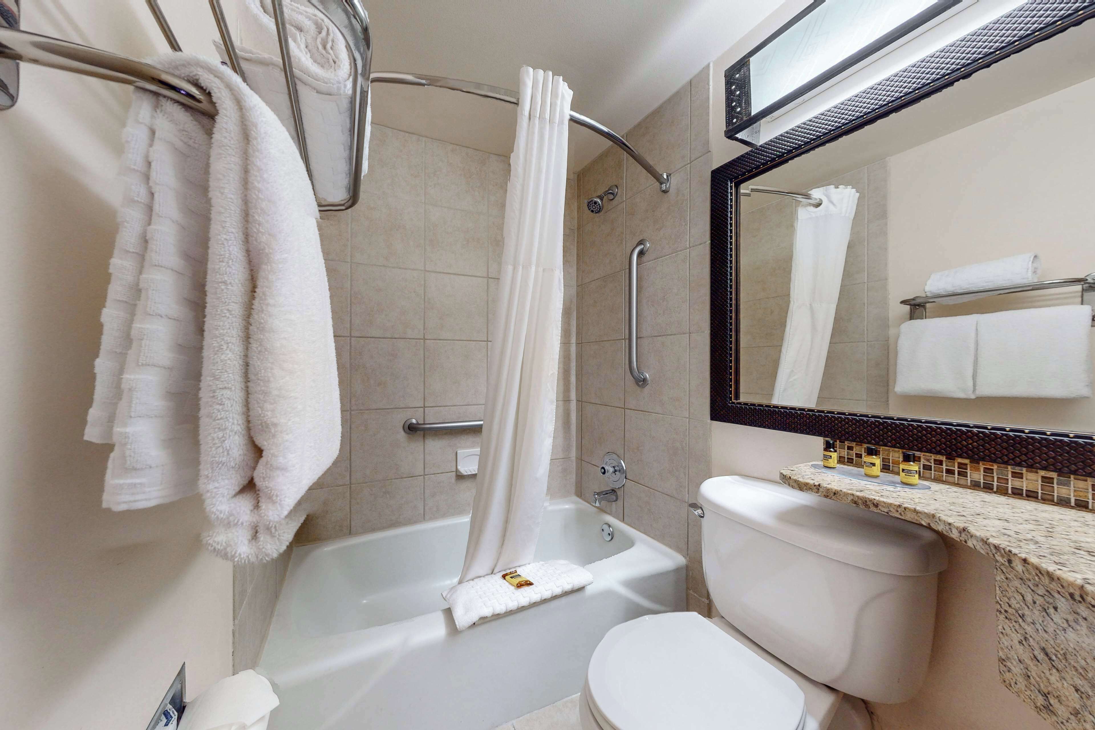 A bathroom with a bathtub, toilet, and a vanity with a mirror.