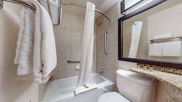 A bathroom with a bathtub, toilet, and a vanity with a mirror.