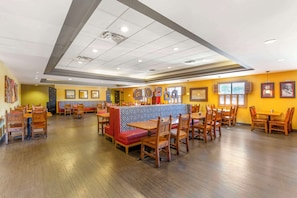 A restaurant with wooden tables and chairs, a counter, and a patterned wall.