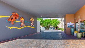 A hotel lobby with a modern design, featuring a large wall mural, a 'Lobby' sign, and a pathway leading to the entrance.
