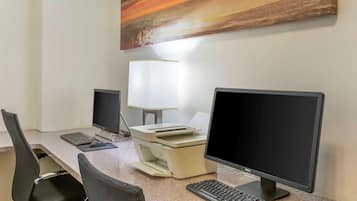 A workspace with two monitors, a printer, a keyboard, and a chair.