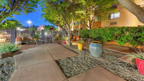 An outdoor patio area with seating, potted plants, and a pathway.