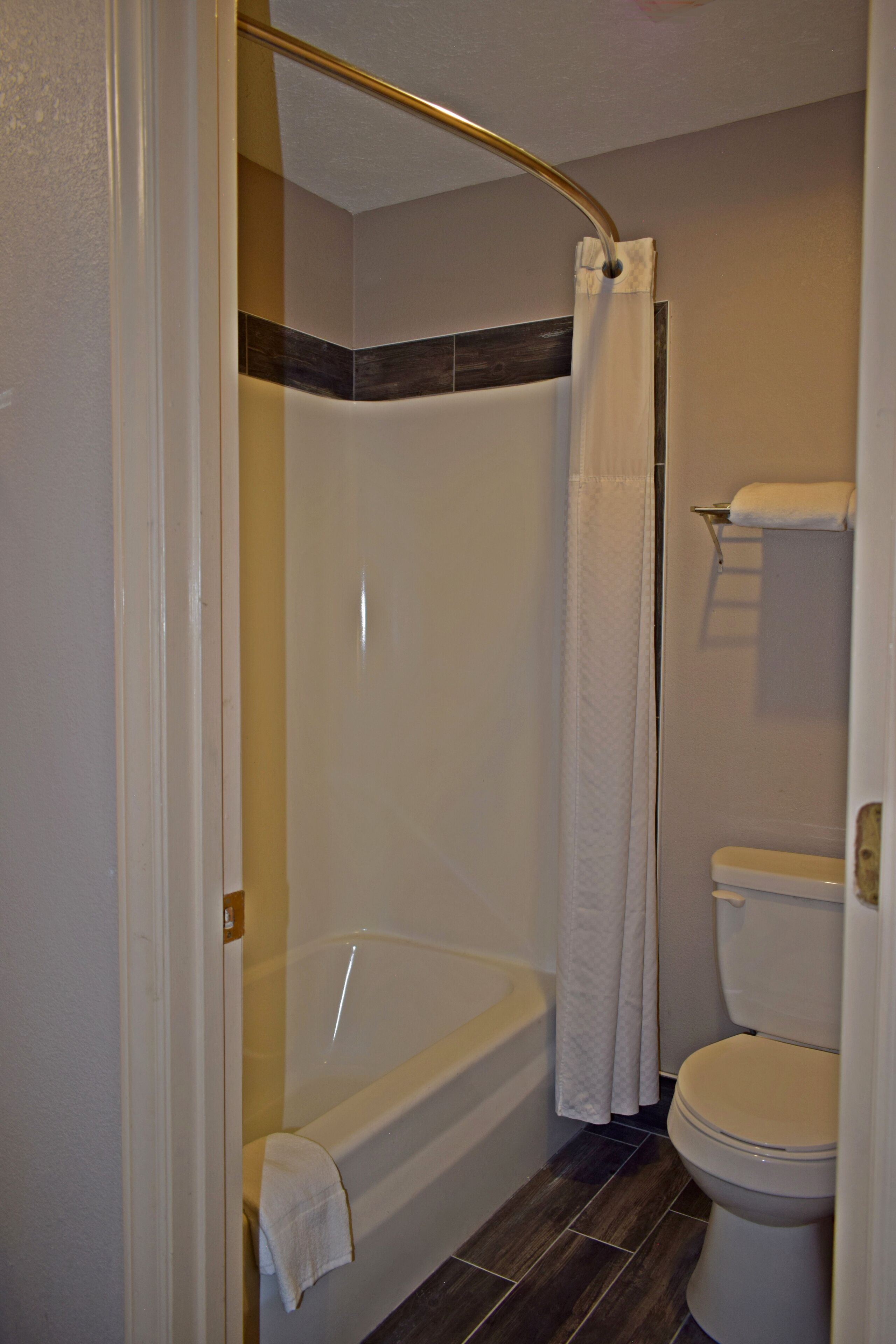 A bathroom with a bathtub, shower curtain, and toilet.
