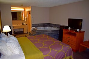 Ein Hotelzimmer mit Bett, Fernseher, Schreibtisch, Kommode, Badezimmer mit Badewanne und Spiegel.