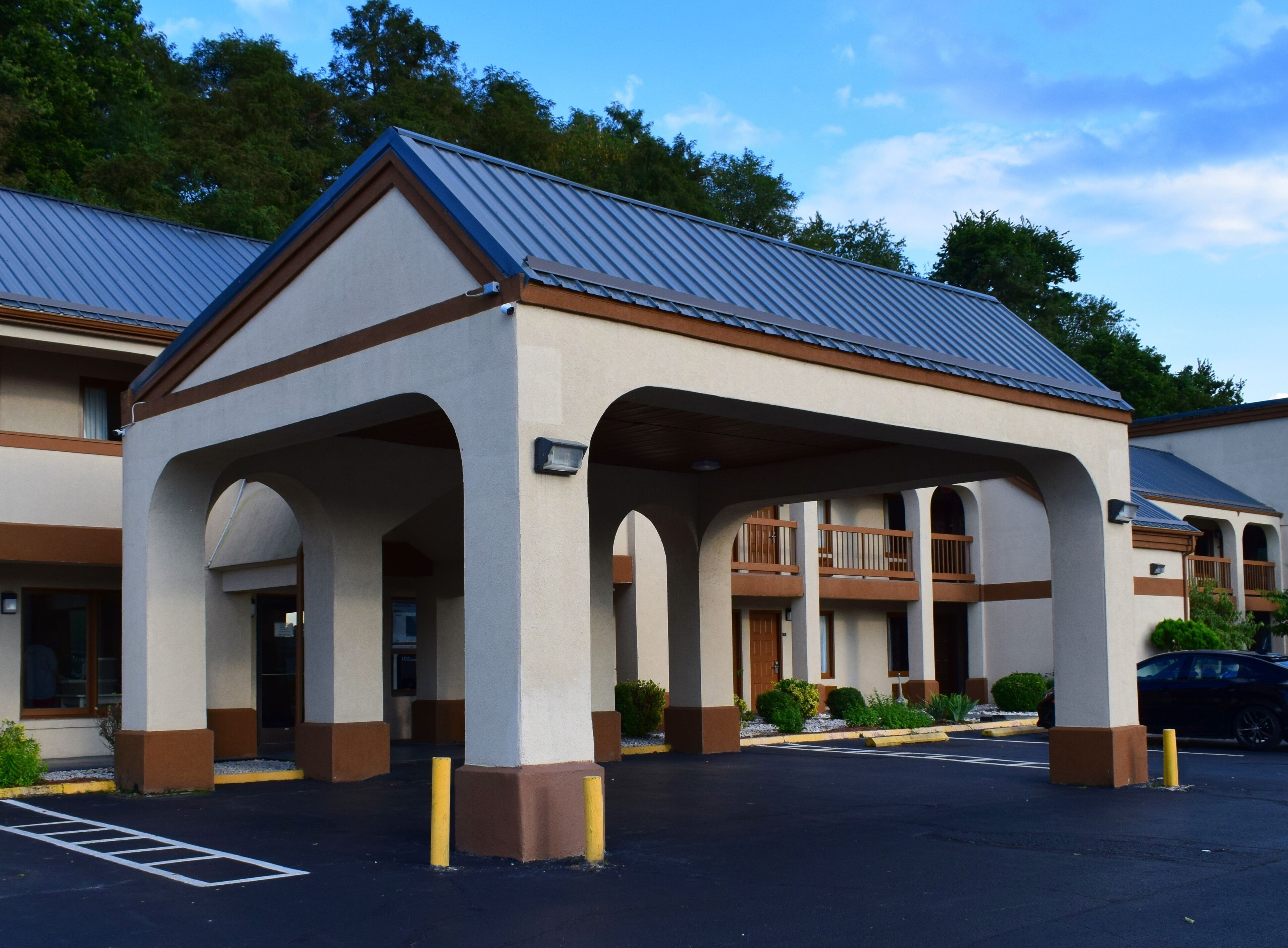 A hotel with a covered outdoor area, multiple balconies, and a parking lot.