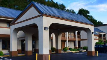 A hotel with a covered outdoor area, multiple balconies, and a parking lot.