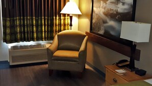 Habitación de hotel con un sillón individual, una lámpara de pie, un calefactor y un cuadro en la pared.