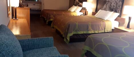 Habitación de hotel con dos camas, un escritorio, una silla y un cuadro grande en la pared.
