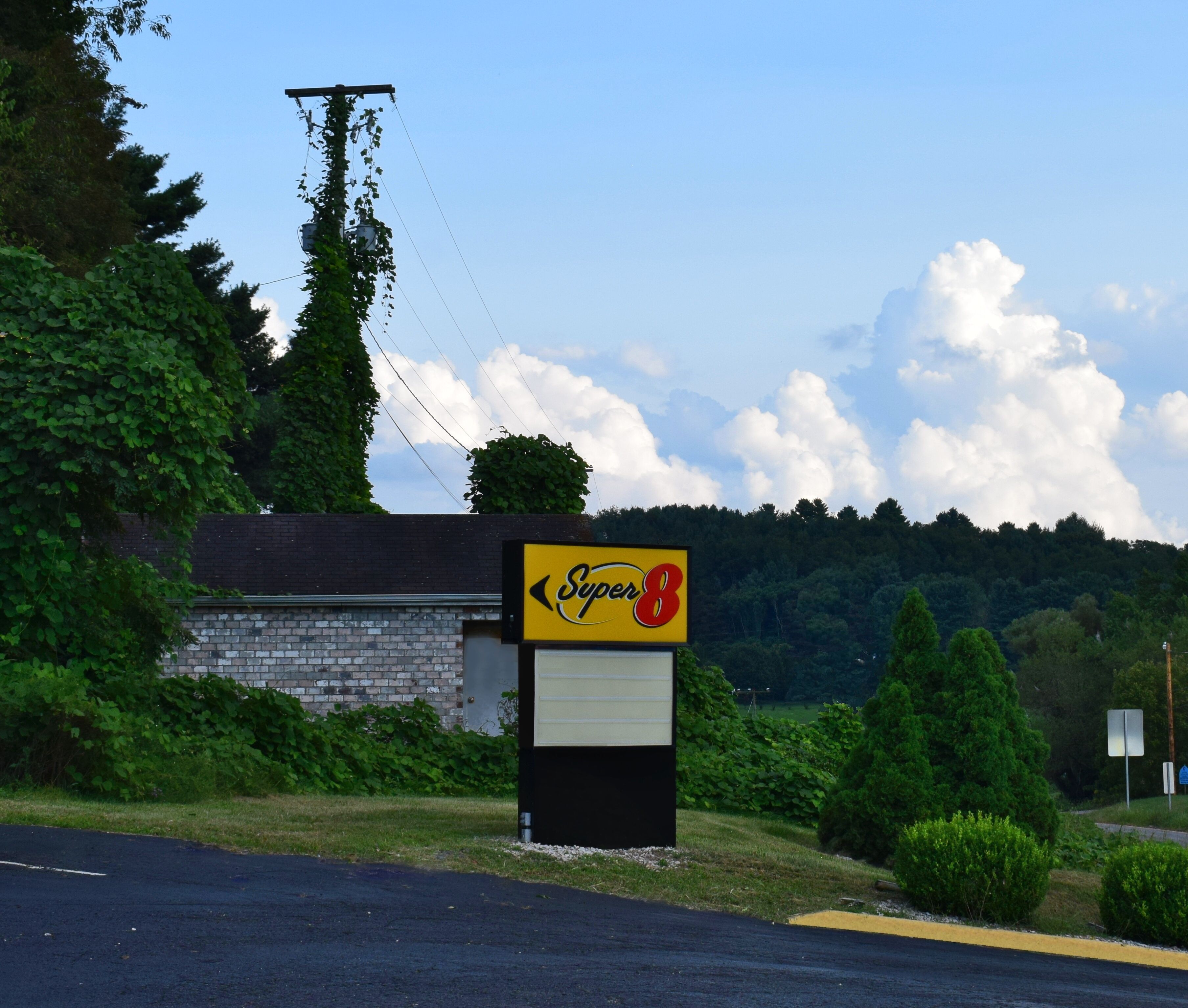 A Super 8 motel sign with a brick building and greenery in the background.