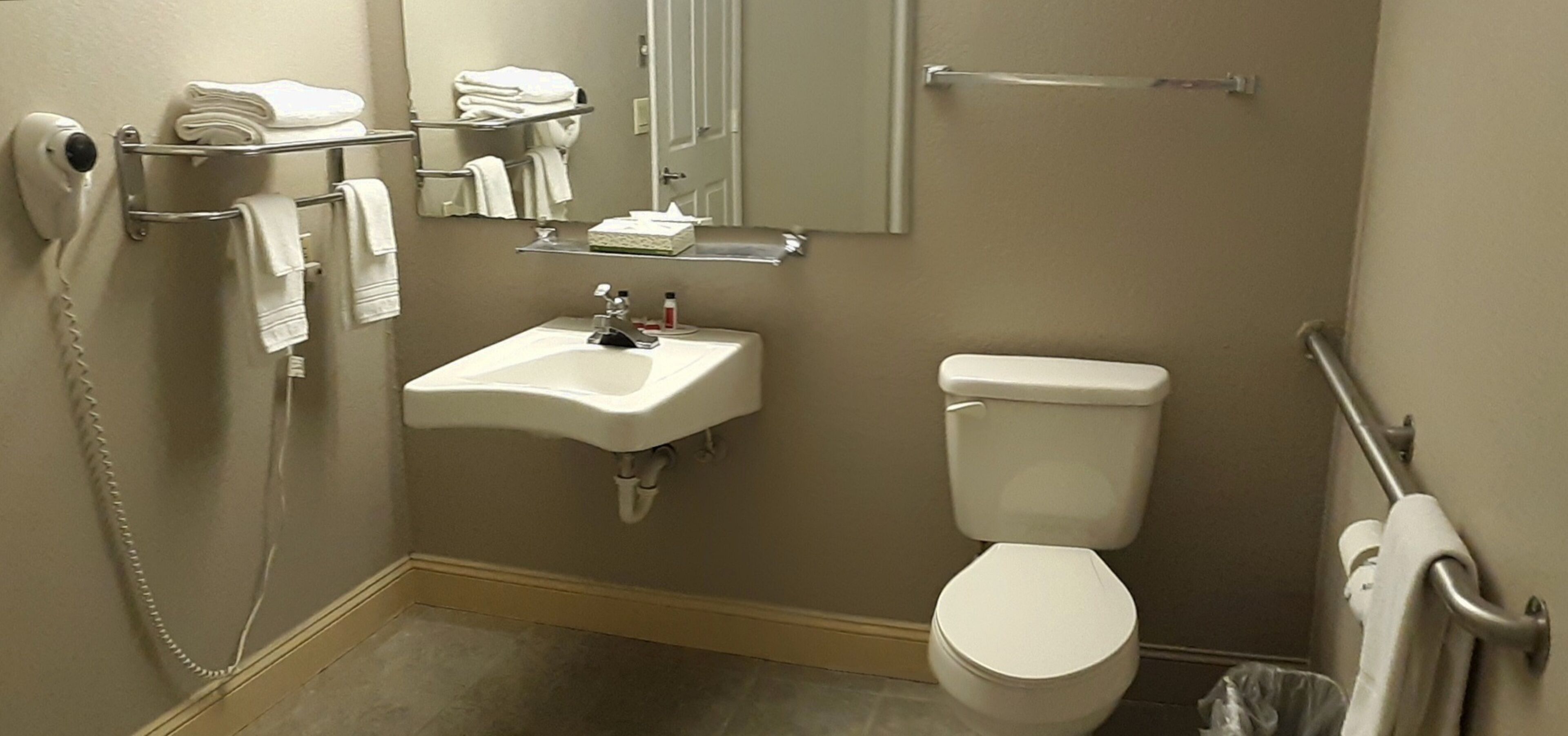 A bathroom with a sink, toilet, towel rack, and a hand dryer.