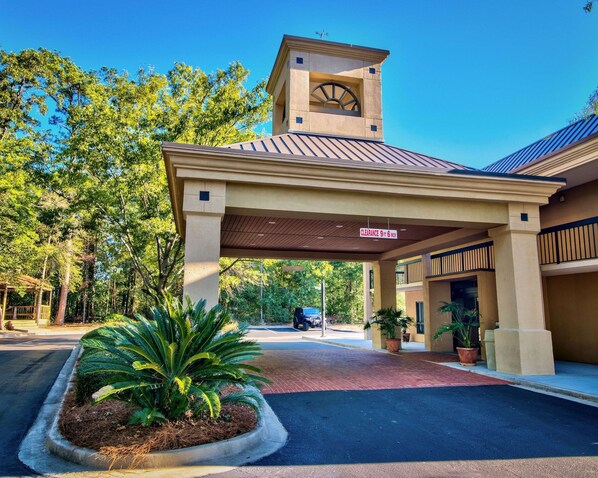 A hotel entrance with a covered walkway, a clock tower, and a sign indicating a clearance of 9 feet 6 inches.
