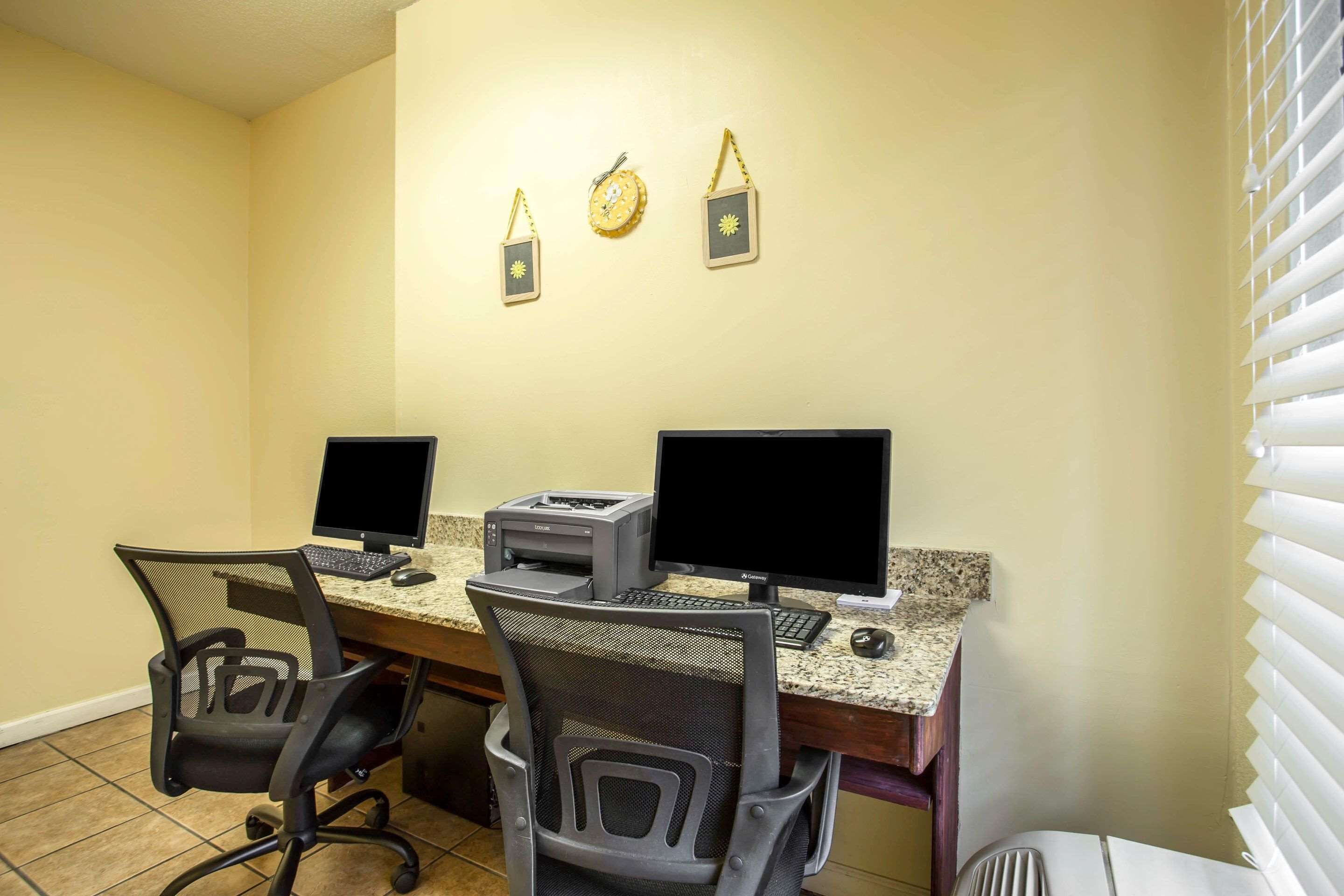 A workspace with two computers, a printer, and two chairs.