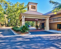 A hotel entrance with a covered walkway, a clock tower, and a sign indicating a clearance of 9 feet.