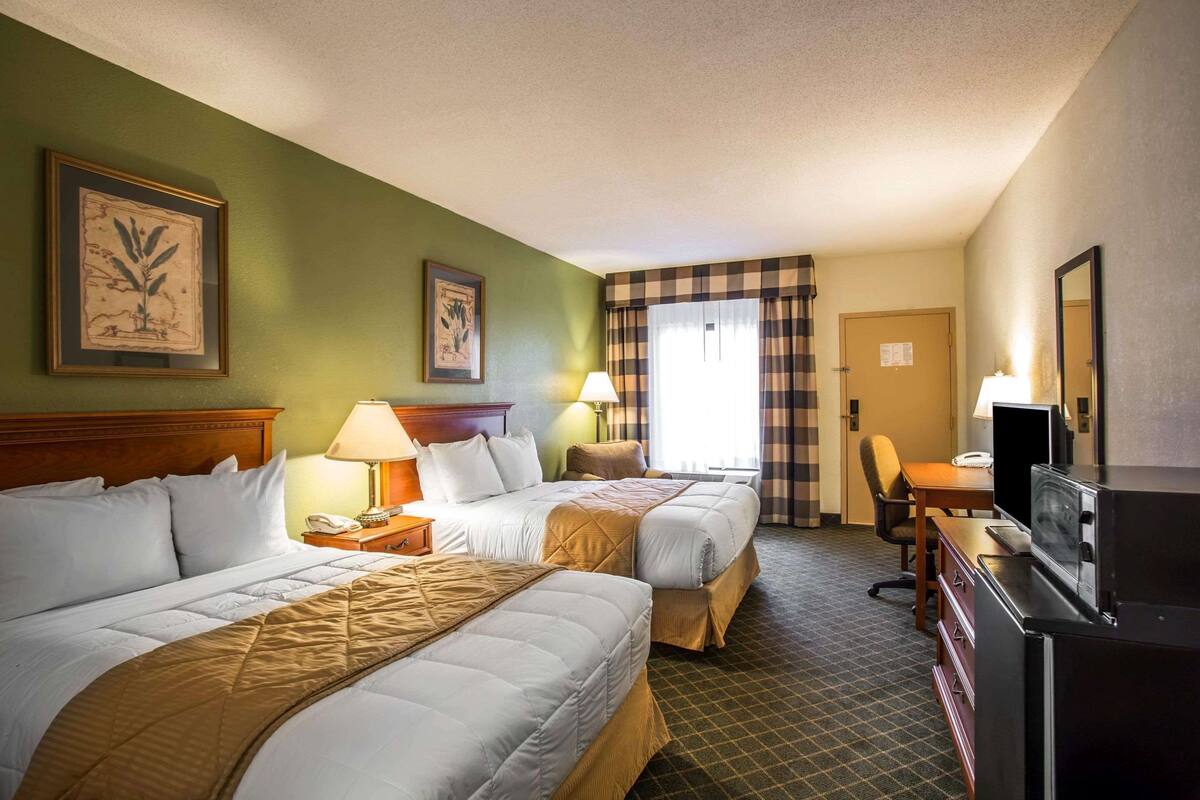 Une chambre d’hôtel avec deux lits, un bureau, une télévision et une chaise.