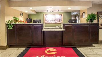 A reception area with a dark wood reception desk, a red carpet with the Clarion logo, a clock on the wall, and a framed picture above the desk.