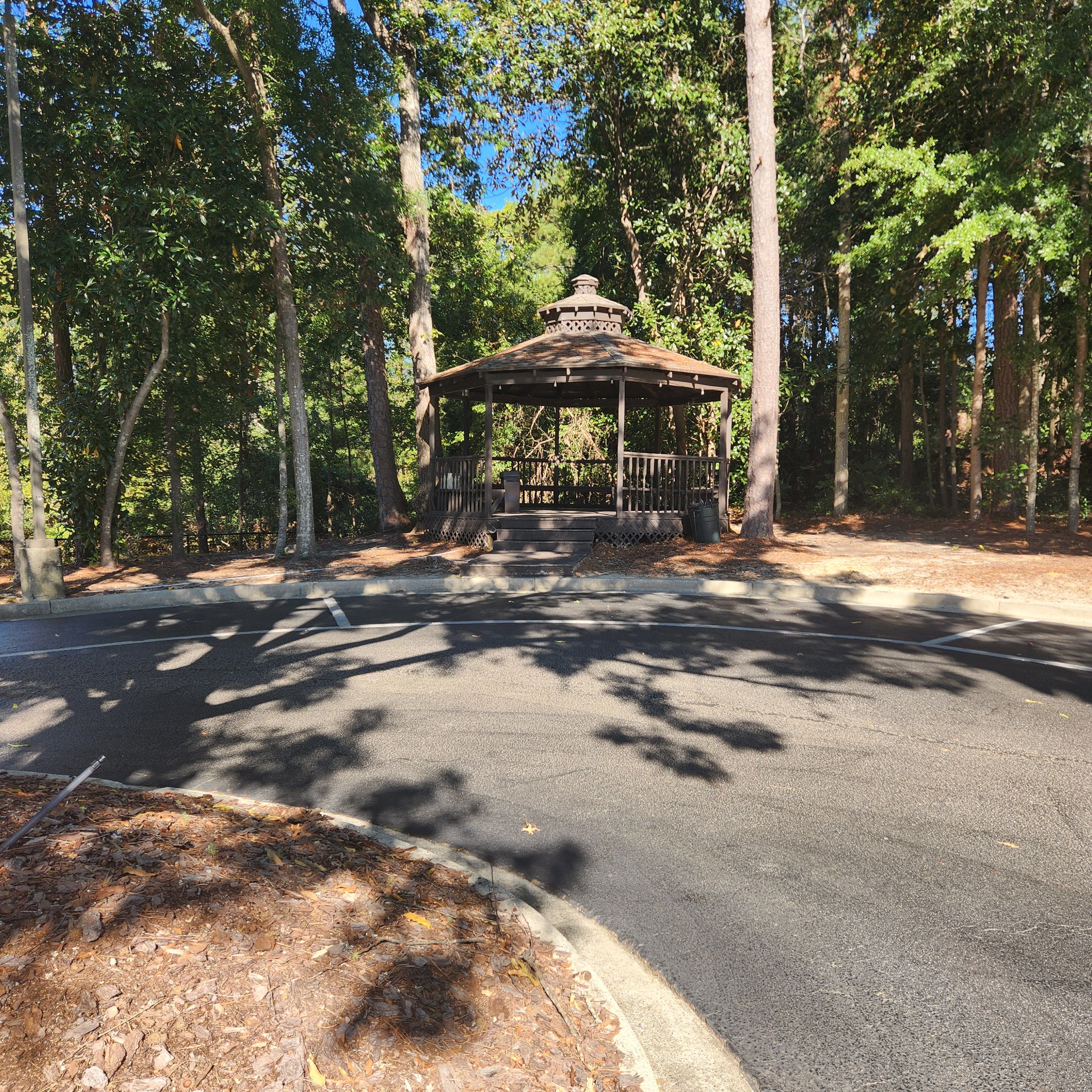 A gazebo in a wooded area with a paved path leading to it.