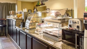 Un comptoir de petit-déjeuner avec divers aliments, un four à micro-ondes et une machine à café.