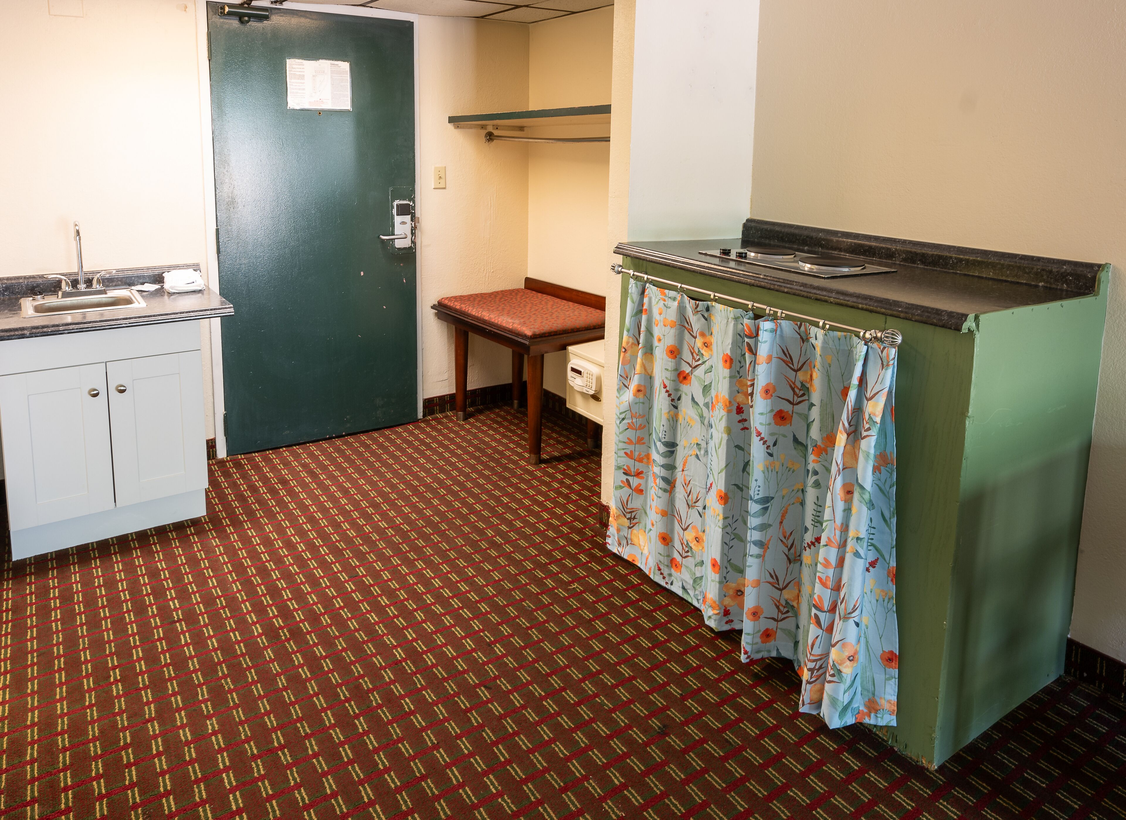Une petite cuisine équipée d’un évier, d’une chaise et d’un rideau de douche.
