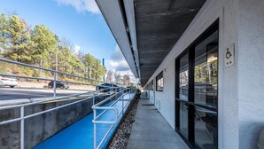 A covered walkway with a blue ramp leading to a building entrance, a wheelchair-accessible sign, and a parking area visible in the background. - Motel 6 Birmingham, AL (Birmingham)