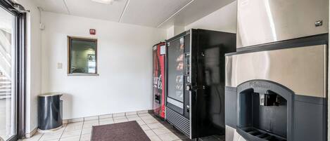 A hotel lobby with a vending machine, a water dispenser, and a trash can.