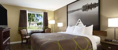 Una habitación de hotel con una cama grande, un escritorio, una silla, un televisor y una ventana con cortinas.