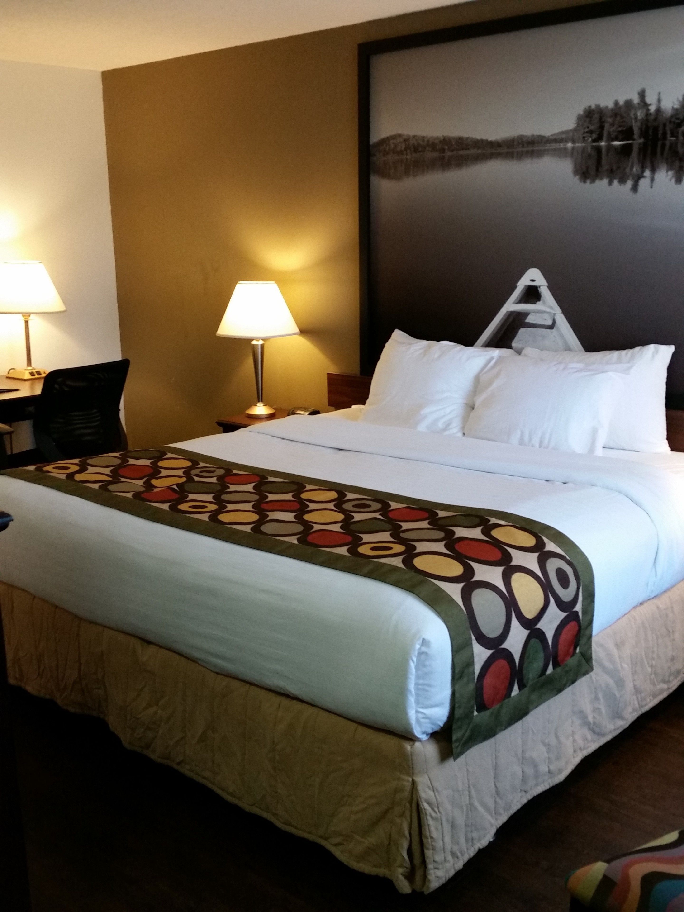 Une chambre d’hôtel avec un grand lit, deux lampes de chevet, un bureau et une chaise.
