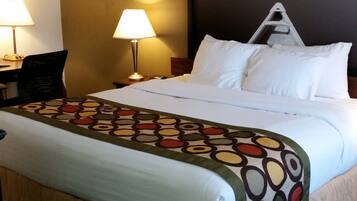 A hotel room with a large bed, two bedside lamps, a desk, and a chair.