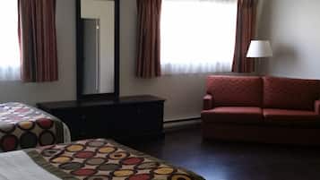 A hotel room with two beds, a sofa, a dresser, and a mirror.