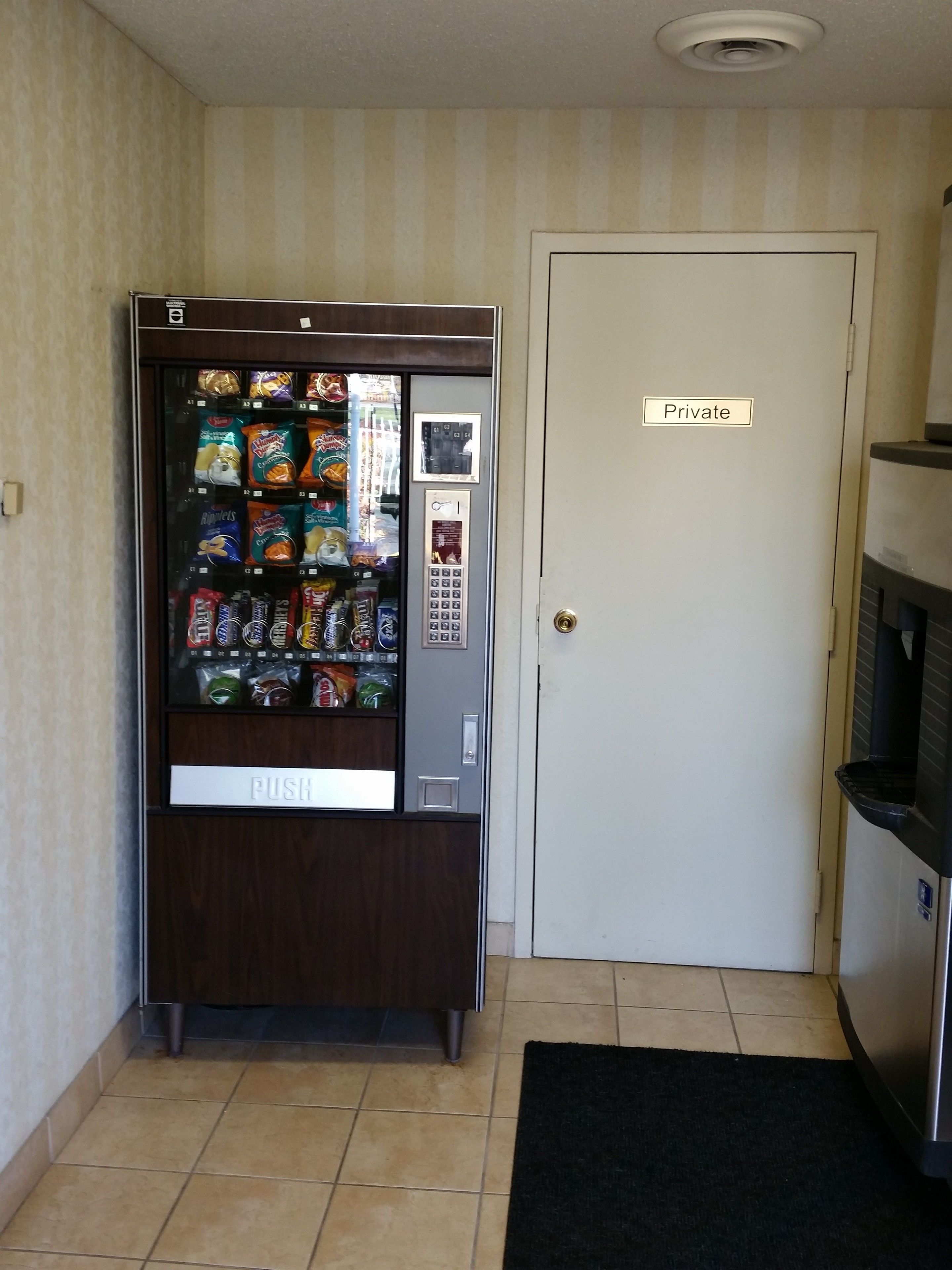 A vending machine with snacks and a private door nearby.
